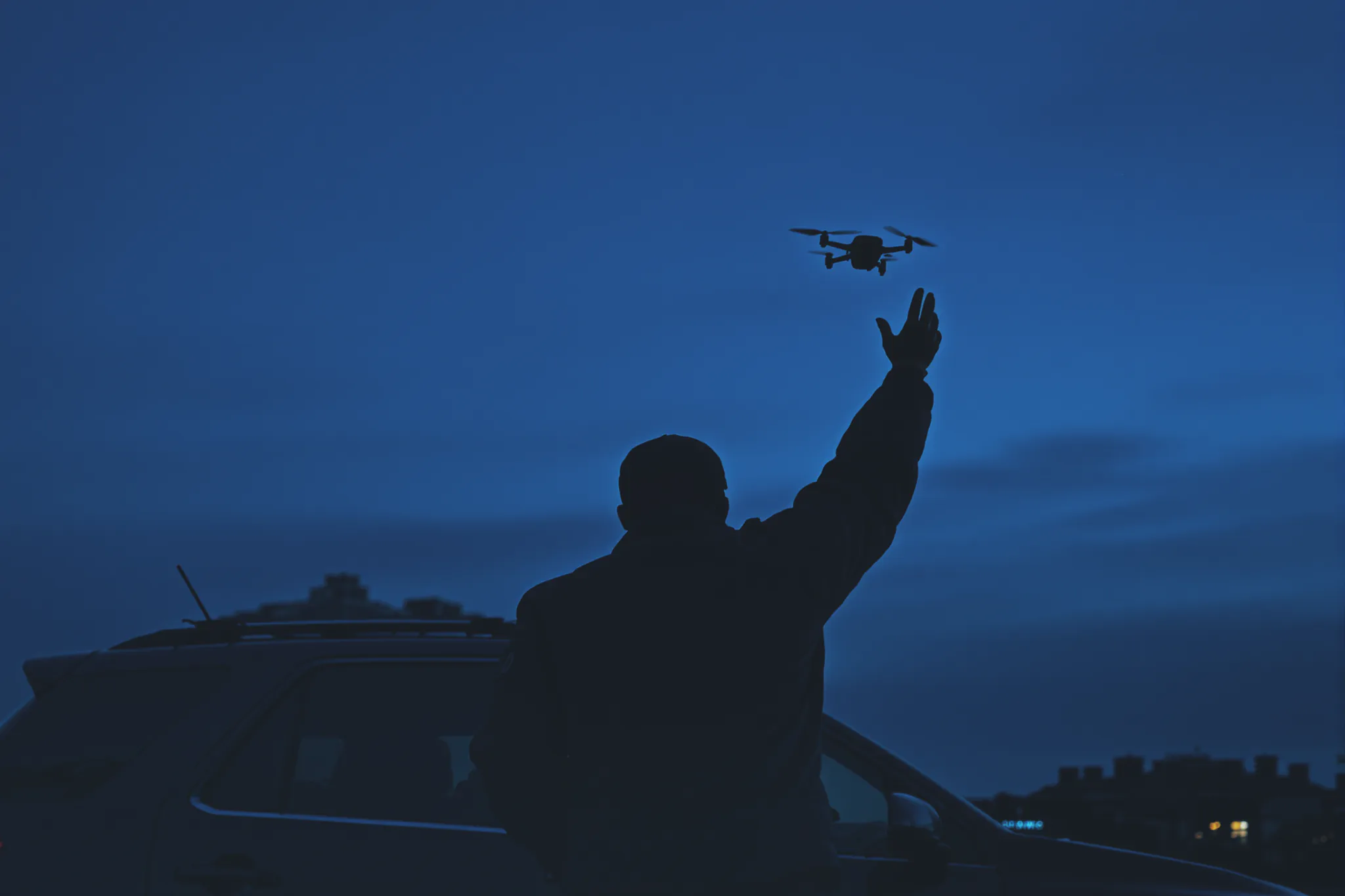 A security officer launching a quadcopter drone at night.